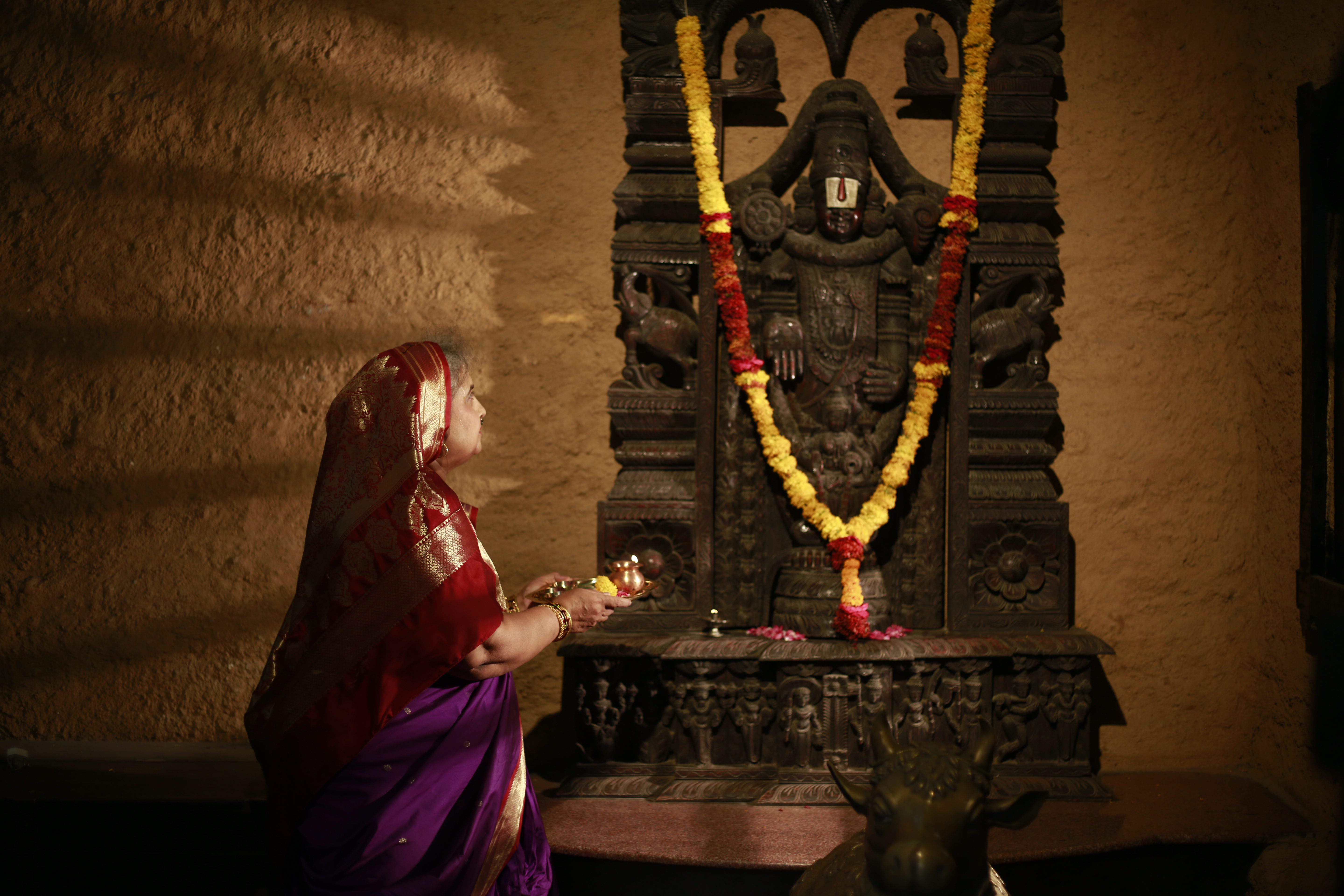 Traditional Indian elder mother offering aarti in the sacred ancestral Maajghar kitchen