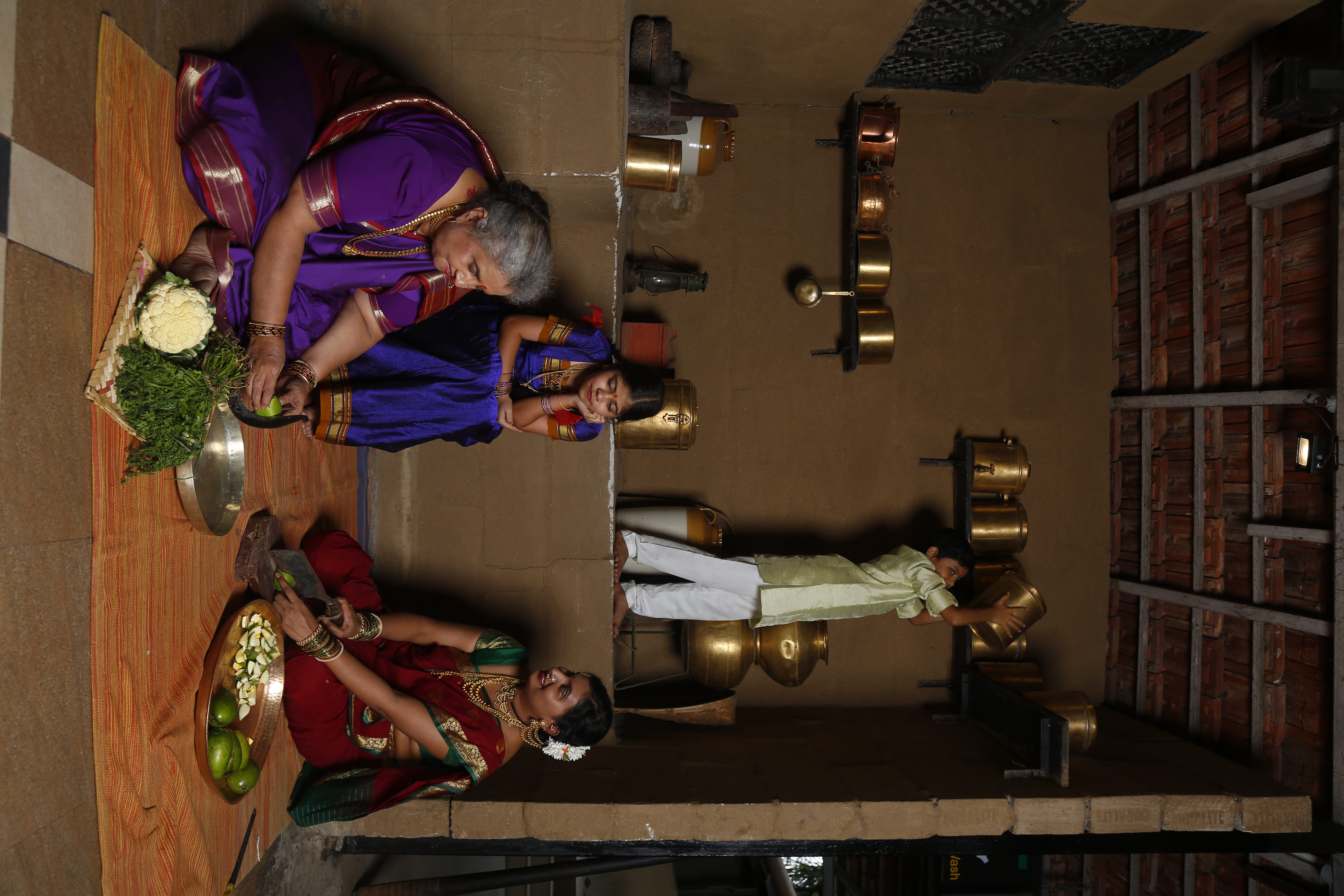 Three generations of women grinding spices together on a traditional stone grinder